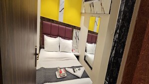 Une chambre d’hôtel comprenant un lit, une table de chevet, un miroir et un appareil de climatisation.