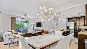 Une cuisine moderne dotée d’un four encastré, d’un coin repas avec une table en marbre et d’un ventilateur de plafond.