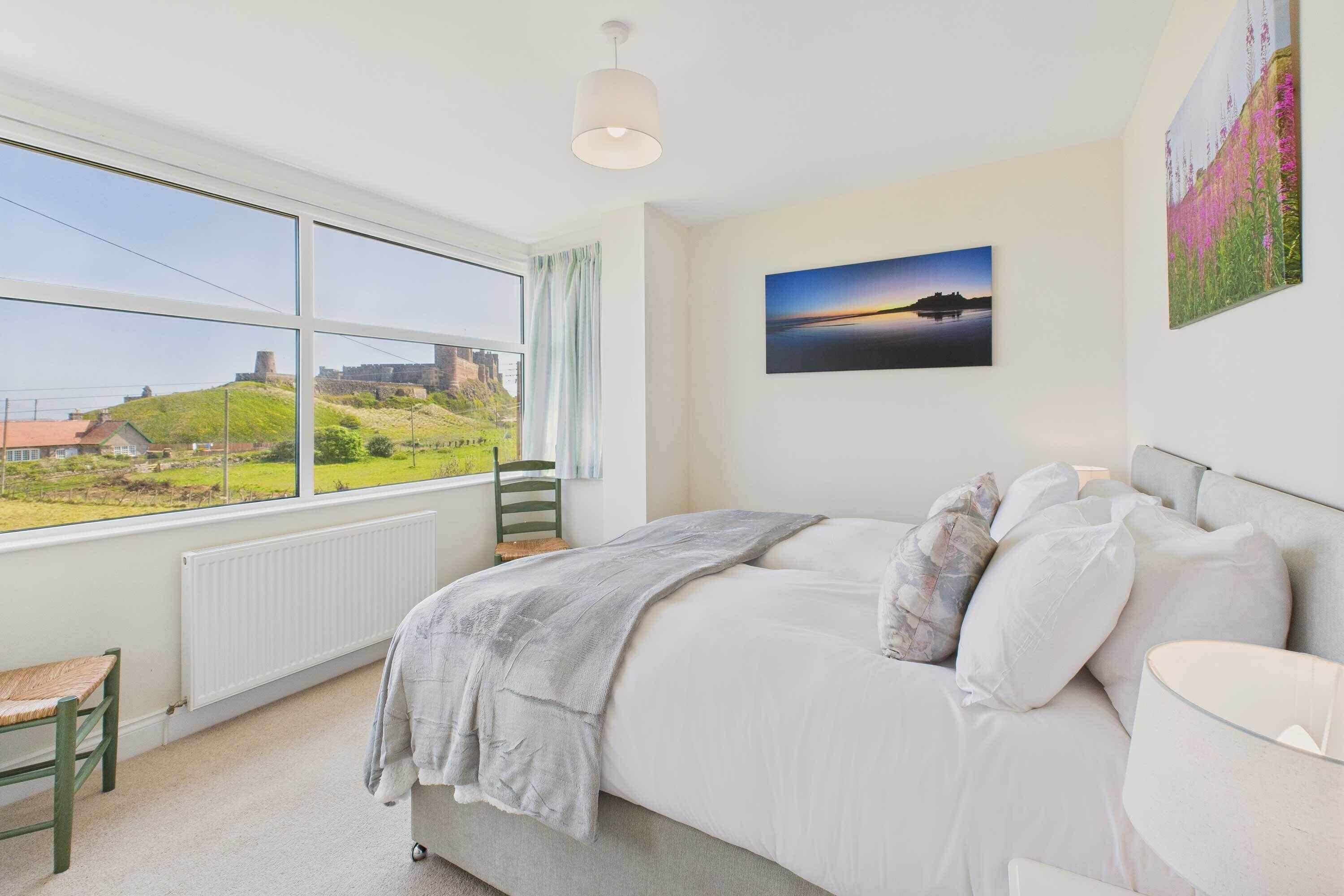 Une chambre avec une grande fenêtre, un lit, une chaise et un radiateur.