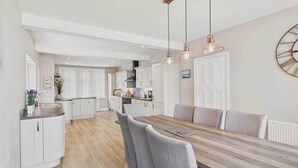 A modern kitchen with white cabinets, a wooden dining table, and pendant lighting. - Host & Stay | Chirnells (Bamburgh)
