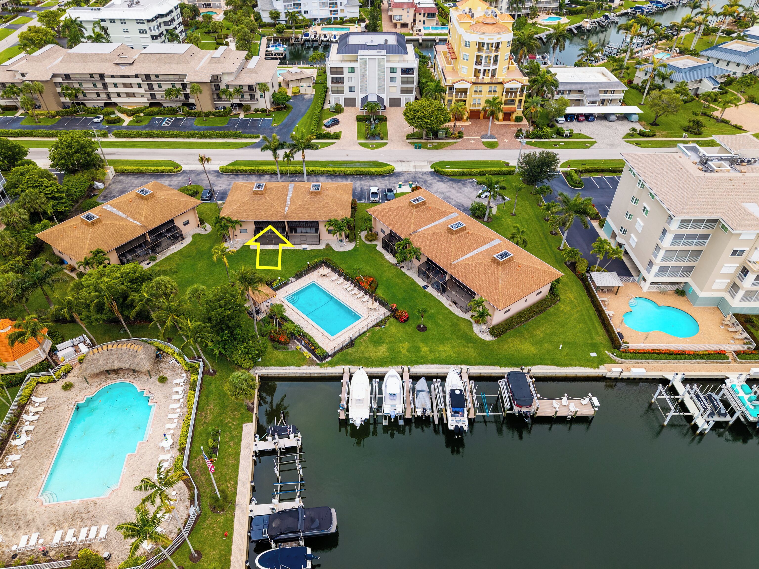 An aerial view of a resort with multiple buildings, a marina, and a swimming pool.