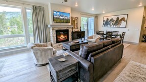 A modern living room with a fireplace, leather sofa, and a dining area. - Views & Trails | Updated Retreat Summer Activities (Keystone)