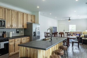 A modern kitchen with wooden cabinets, stainless steel appliances, a central island with stools, and a dining area with a ceiling fan. - NEW LISTING | 3BR | 2.5 bath, Mountain Views, 1 Mile to downtown (Leadville)