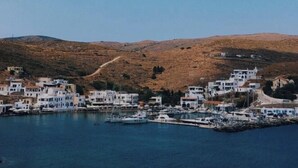 A coastal town with white buildings, a marina, and hills in the background. - Seafront Alos Gem - Loutra Seaview Escape (Loutra)