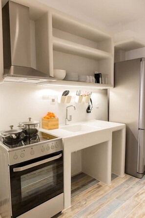 Una cocina moderna con horno empotrado, refrigerador de acero inoxidable y encimera blanca.