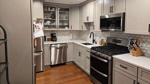 A modern kitchen with stainless steel appliances, white cabinetry, and a tiled backsplash. - Classy Old Town Getaway, 3-BR in Perfect Location (Alexandria)