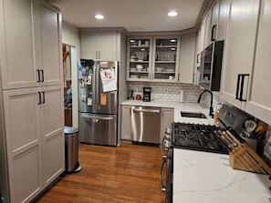 Uma cozinha moderna com eletrodomésticos de aço inoxidável, armários brancos e bancada de mármore.