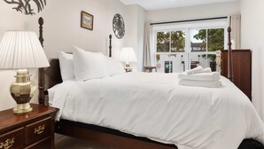 A hotel room with a bed, two bedside lamps, a ceiling fan, and a view of the street outside. - Classy Old Town Getaway, 3-BR in Perfect Location (Alexandria)