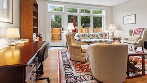 A spacious living room with a wooden desk, a sofa, a chair, and a ceiling fan. - Classy Old Town Getaway, 3-BR in Perfect Location (Alexandria)