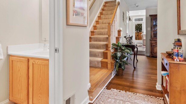A home interior with a wooden staircase, a kitchen area with wooden cabinets, and a dining area with a table and chairs. - Classy Old Town Getaway, 3-BR in Perfect Location (Alexandria)