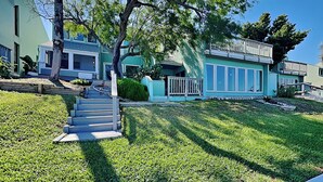 A two-story house with a front porch, a staircase leading to the entrance, and a well-maintained lawn. - Watercolor Skies | Cozy, Waterfront (Corpus Christi)