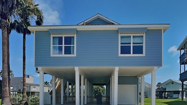 A two-story residential building with a covered front porch and a garage. - Papa's Paradise | Partial Beach Views (Galveston)