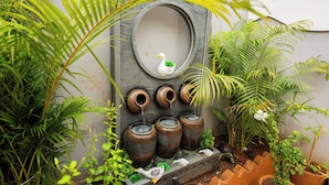 A decorative wall with a mirror, three water spouts, and a small duck figurine.