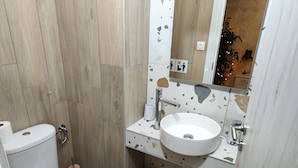 Une salle de bain équipée de toilettes, d’un lavabo et d’une douche.