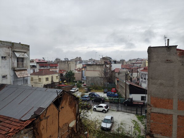 Zona residencial con varios edificios, algunos con balcones y otros con techos planos. Se ven coches aparcados y un camión.