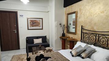Quarto com cama, sofá, mesa pequena, espelho e porta.