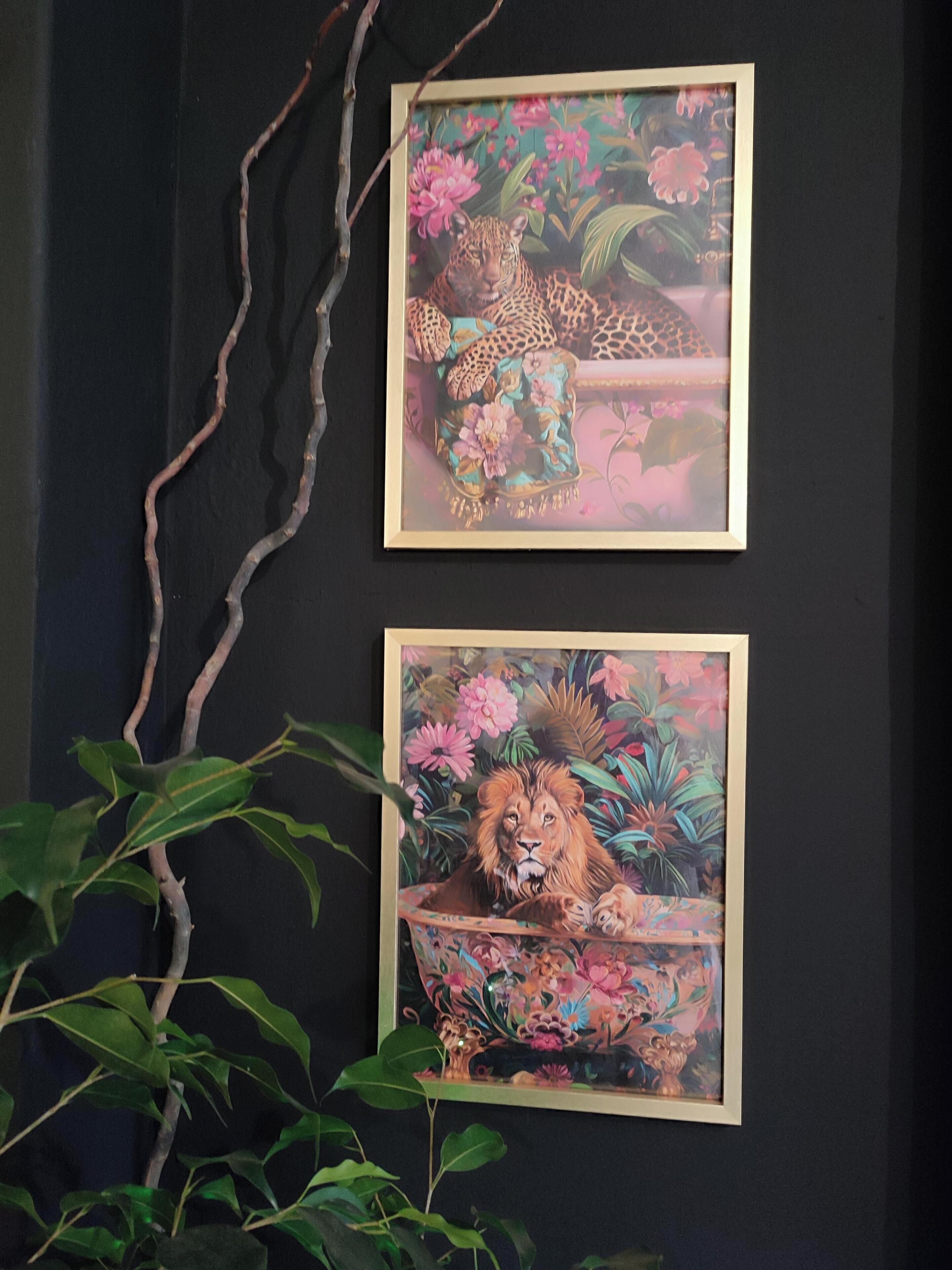 Two framed paintings of a leopard and a lion on a dark wall.