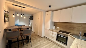 Eine moderne Küche mit Holzarbeitsplatte, integriertem Backofen und weißen Schränken. Ein Essbereich mit Holztisch und Stühlen ist ebenfalls vorhanden.