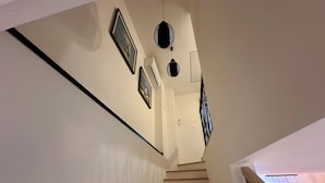 Eine Treppe mit Holzdielen und einer weißen Wand mit gerahmten Bildern sowie einem schwarzen Dekorationsgegenstand.