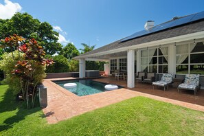 Ein moderner Poolbereich im Freien mit überdachter Terrasse und Liegestühlen.
