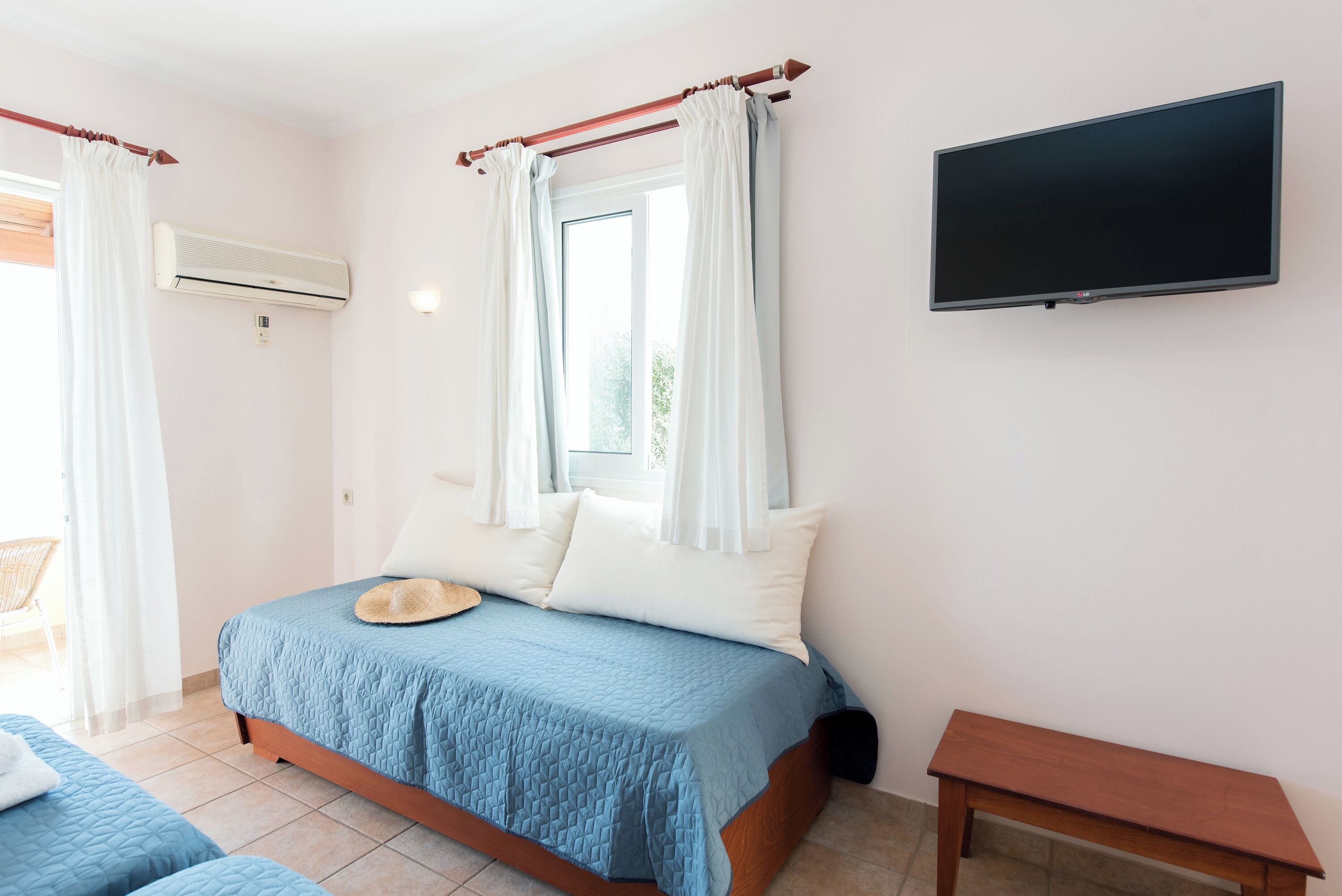 Une chambre à coucher avec un lit, une télévision et une fenêtre avec des rideaux.