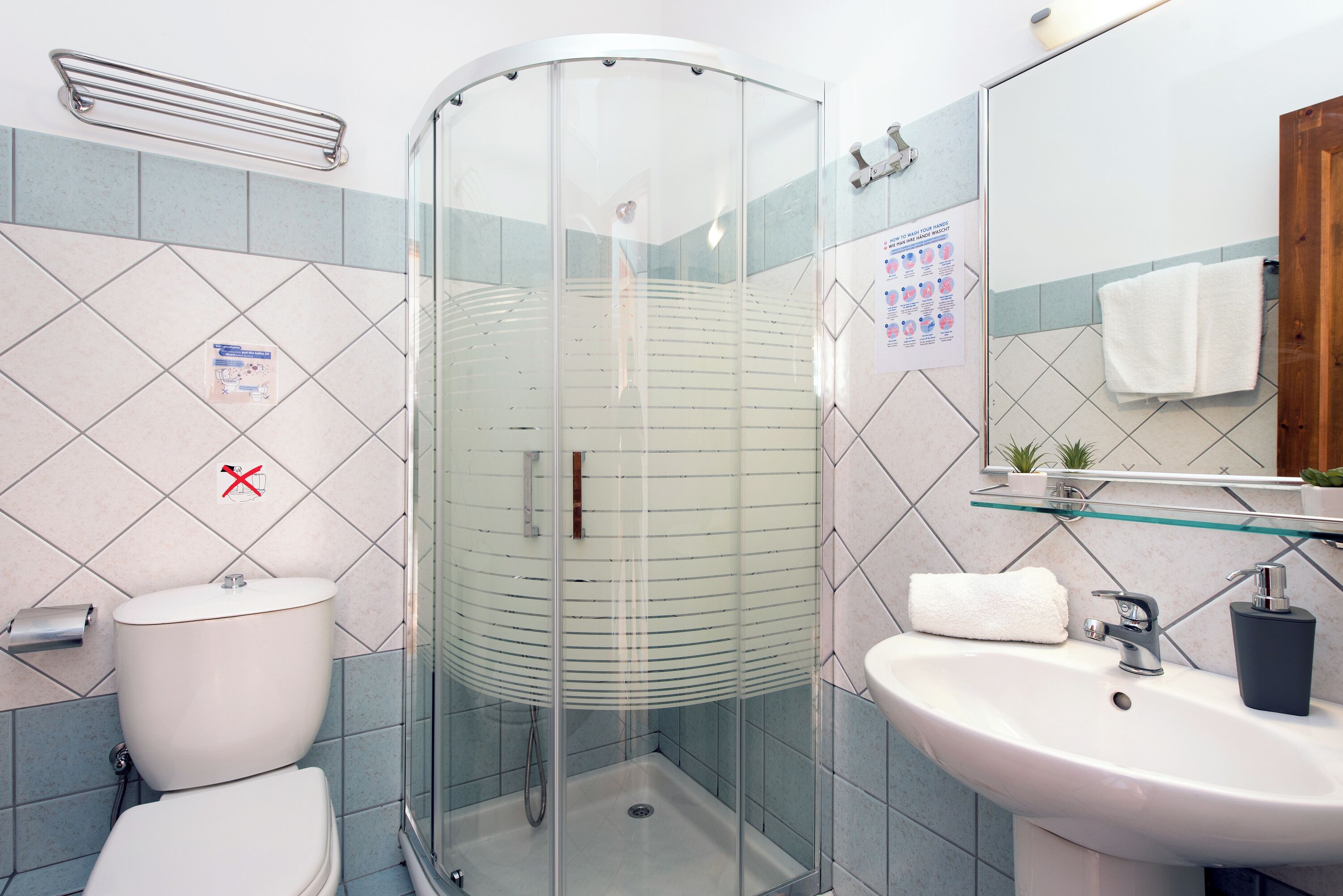 Un baño con ducha de vidrio, inodoro, lavamanos y espejo.