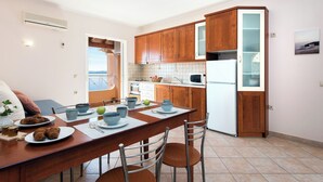 A modern kitchen with wooden cabinets, a white refrigerator, and a dining area with a table set for two.