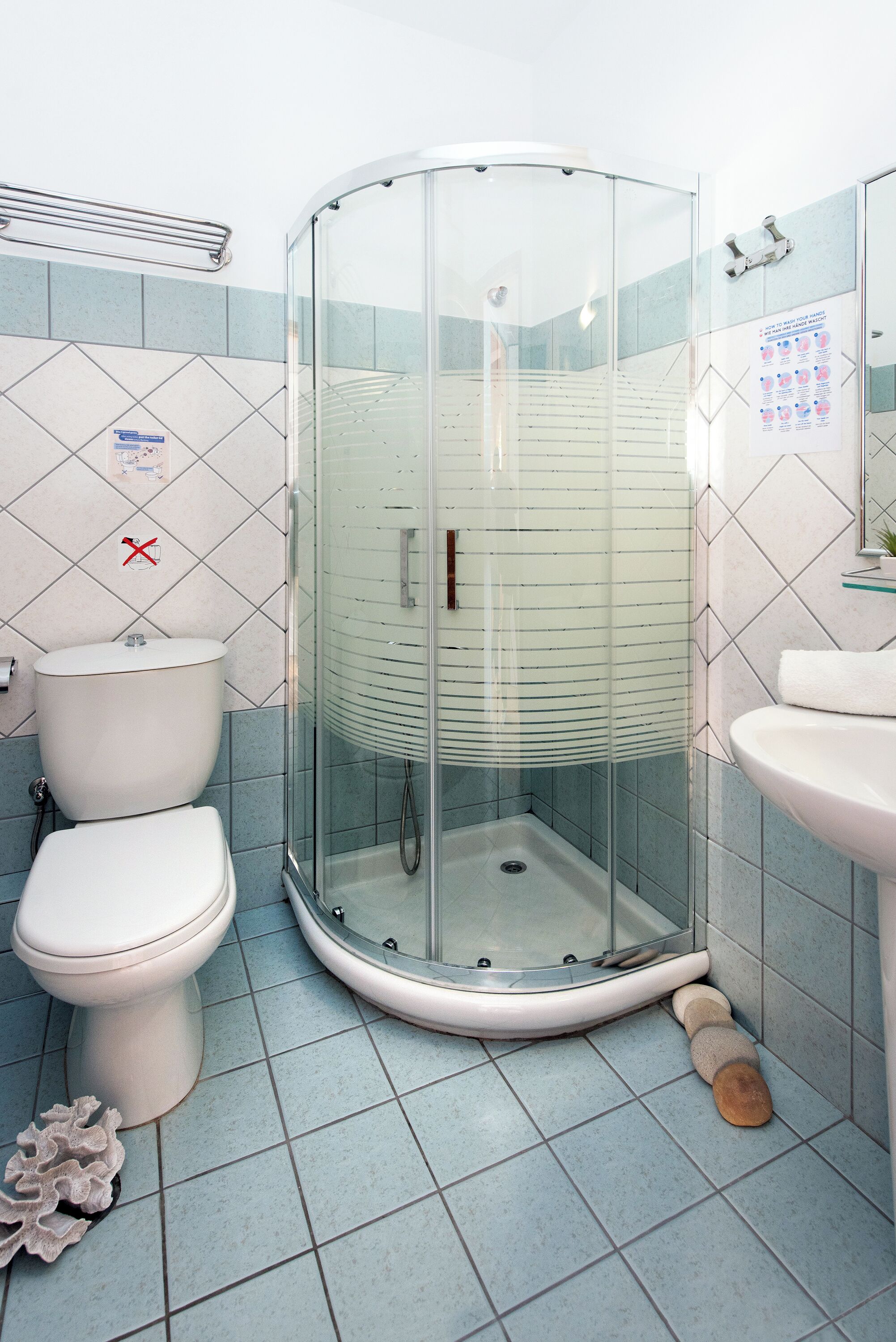 A bathroom with a glass-enclosed shower, a toilet, and a sink.
