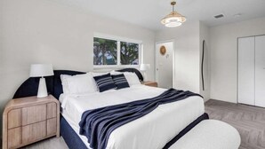 A modern bedroom with a bed, bedside tables, a wardrobe, and a window. - 4br Biscayne River Home: Pool & Pickleball Fun 4 Bedroom Home (North Miami Beach)