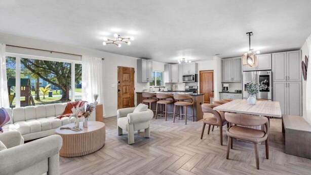 A modern living space with a kitchen, dining area, and seating area. - 4br Biscayne River Home: Pool & Pickleball Fun 4 Bedroom Home (North Miami Beach)