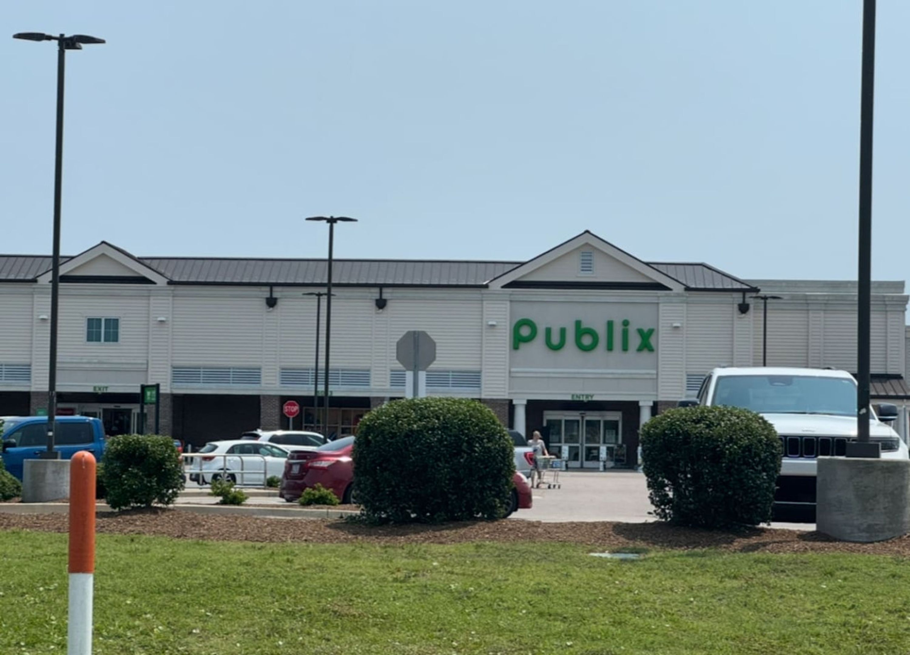 A Publix store with a parking lot, cars, and a clear sky.