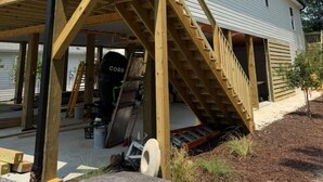 Una casa de dos pisos con un porche de madera y una escalera que conduce al segundo piso.