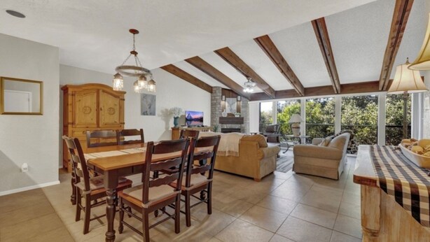 Amplia sala de estar con mesa y sillas de comedor, un sofá y una cocina con chimenea de piedra.