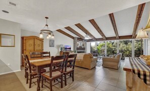 Amplia sala de estar con mesa y sillas de comedor, un sofá y una cocina con chimenea de piedra.