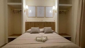 A bedroom with a bed, headboard, bedside tables, and wall-mounted lamps.