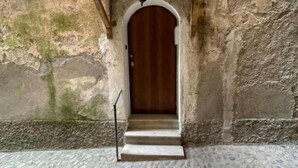 A stone building with a wooden door and a small set of steps leading up to it.