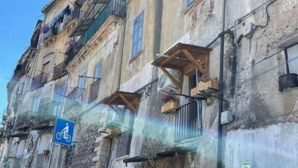 A historic building with multiple balconies, a blue bicycle parking sign, and a weathered facade.