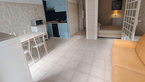 A compact room with a kitchenette, a dining area, and a bed.