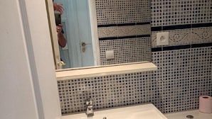 A bathroom with a tiled backsplash, a sink, a mirror, and a toilet.