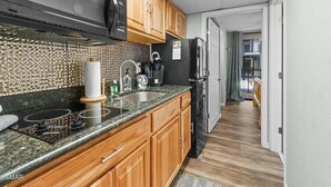 A modern kitchen with wooden cabinets, a black microwave, and a stainless steel sink. - Slopeside Serenity 111–Cabin Vibe–Sleeps 4 (Gatlinburg)