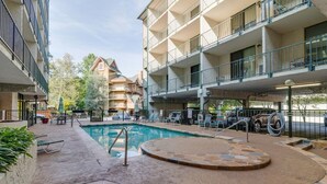 A hotel courtyard with a swimming pool, outdoor seating, and a stone-tiled hot tub. - Slopeside Serenity 111–Cabin Vibe–Sleeps 4 (Gatlinburg)