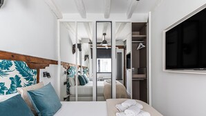 A bedroom with a bed, a mirror, a wardrobe, and a TV. - Waou Gran Via VII - Alquiler Corta Duración (Madrid)