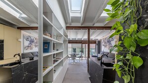 A modern interior with a central walkway, white shelving units, and a view through large windows. - Waou Gran Via VII - Alquiler Corta Duración (Madrid)