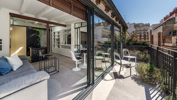 A modern apartment with a balcony, furnished with a sofa, chairs, and a table. - Waou Gran Via VII - Alquiler Corta Duración (Madrid)