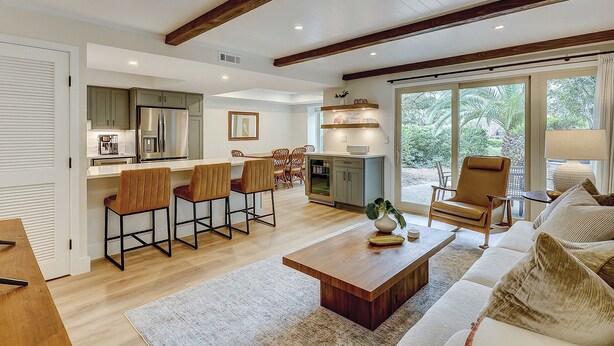 A spacious living area with a wooden coffee table, a sofa, and a dining area with bar stools. - Sunset Rentals- Bluff Villas 1678 (Hilton Head Island)