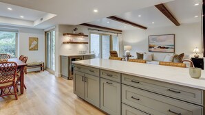 A modern kitchen with a large island, wooden chairs, and a dining table. - Sunset Rentals- Bluff Villas 1678 (Hilton Head Island)