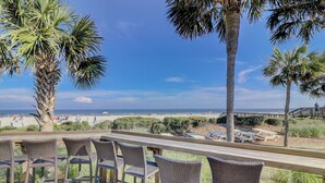 A beachside patio with wicker chairs and a wooden deck overlooking the ocean. - Sunset Rentals- Bluff Villas 1678 (Hilton Head Island)
