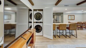 A modern kitchen with built-in appliances, a dining area with wooden chairs, and a laundry room with stacked washers and dryers. - Sunset Rentals- Bluff Villas 1678 (Hilton Head Island)