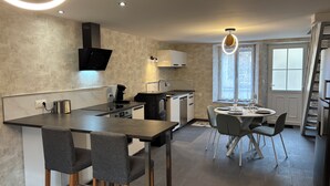 Une cuisine moderne dotée d’un îlot central, de tabourets de bar et d’un coin repas avec une table ronde et des chaises.