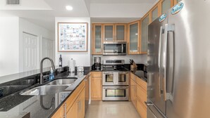 Eine moderne Küche mit Edelstahlgeräten, Holzschränken und einer schwarzen Granitabdeckung.